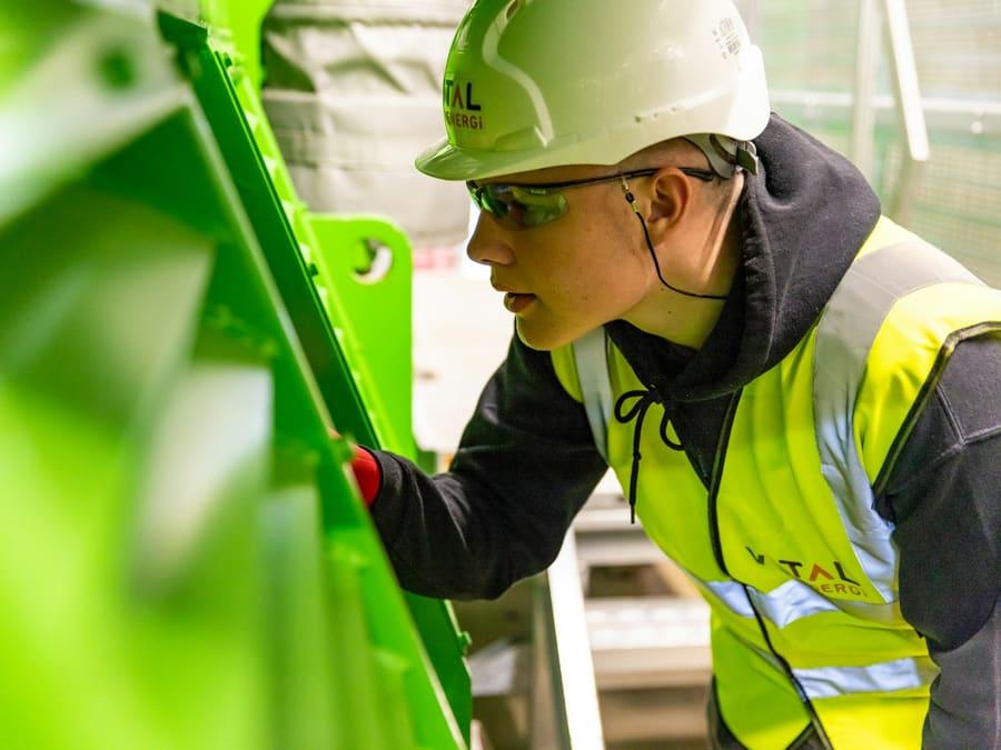 A young tradesperson in a hard hat inspecting equipment