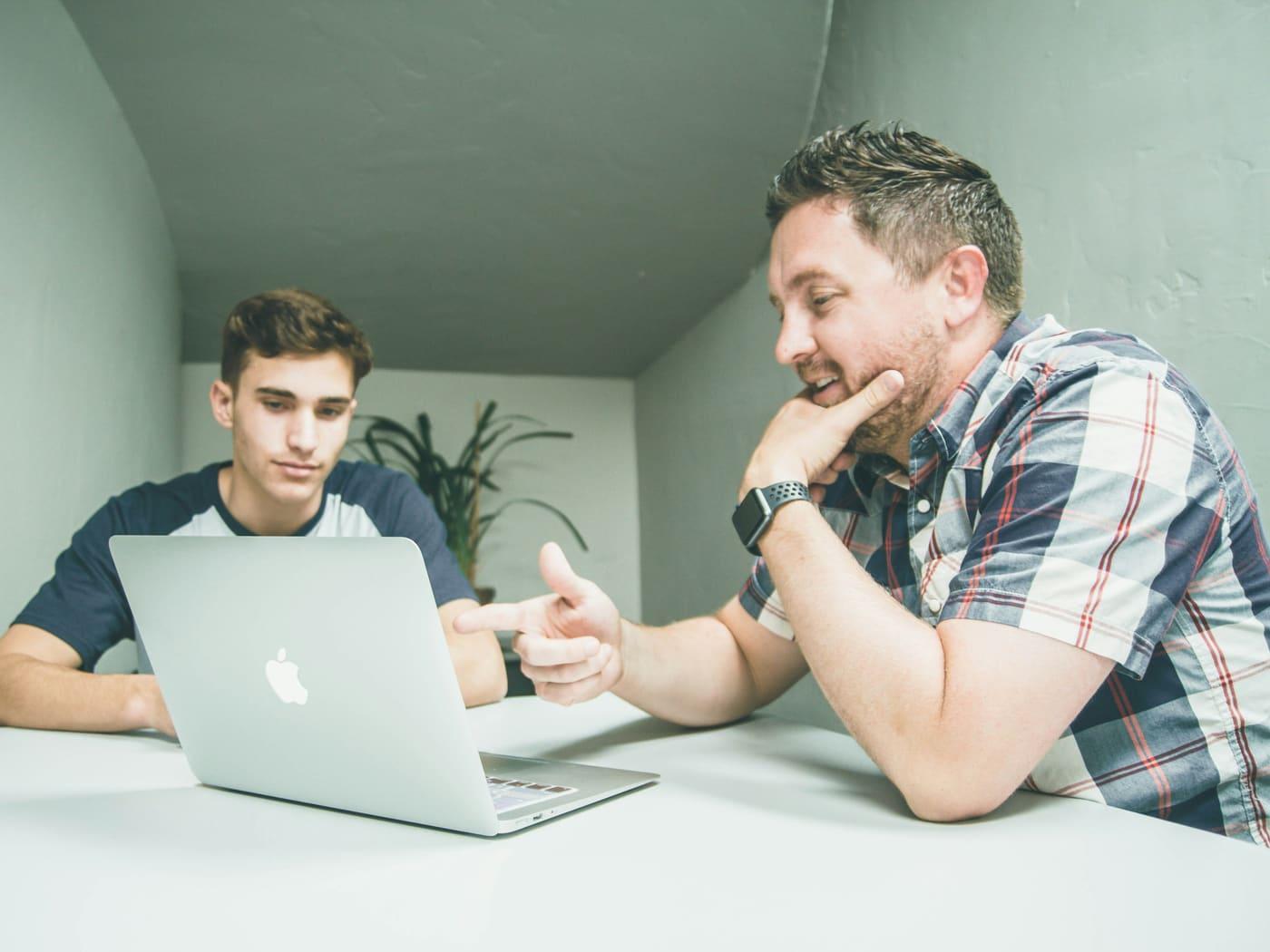 A student and an adult mentor working together at a laptop